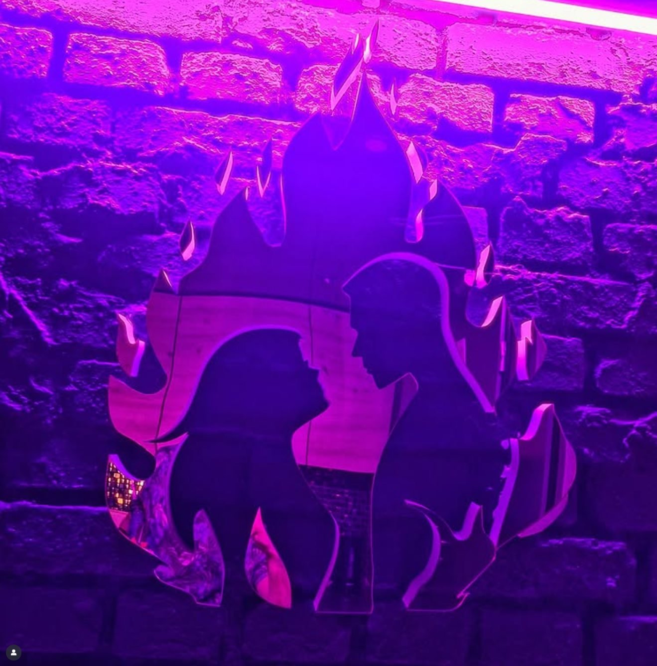 Neon z sylwetkami pary na ceglanej ścianie w apartamencie Secret