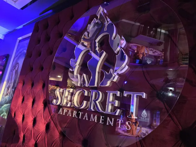 Logo Secret Apartments na pikowanym zagłówku łóżka