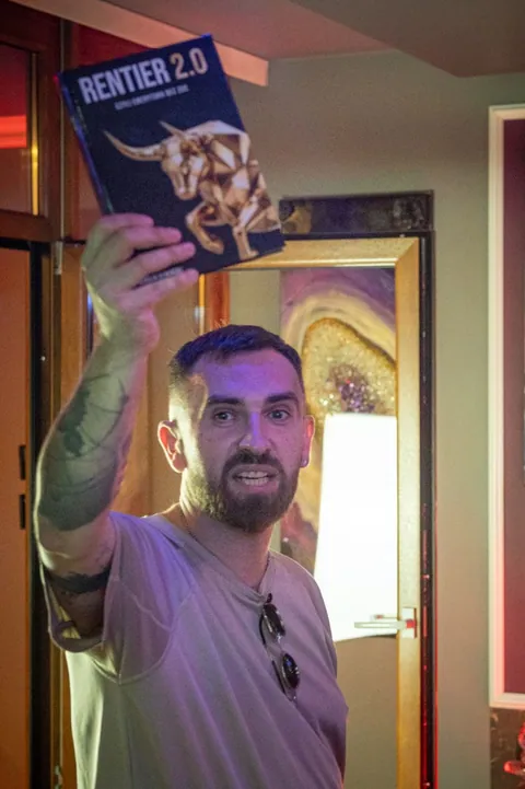 Gość pokazuje książkę Rentier 2.0 podczas wieczoru w Secret Apartments