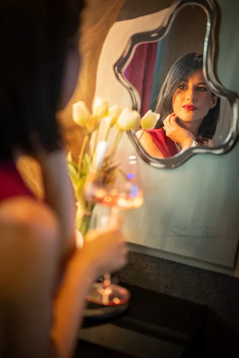 Kobieta w lustrze z lampką wina i tulipanami